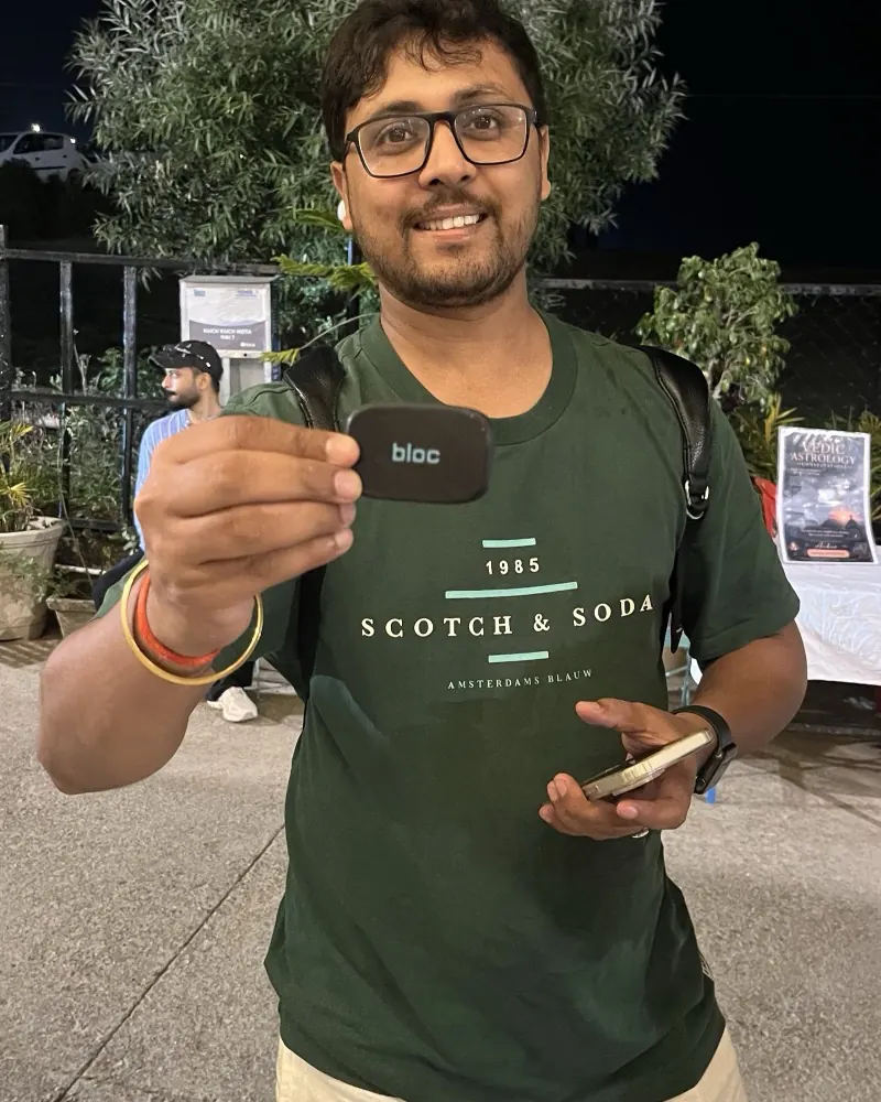 A smiling bloc owner in glasses at night, holding his bloc toward the camera