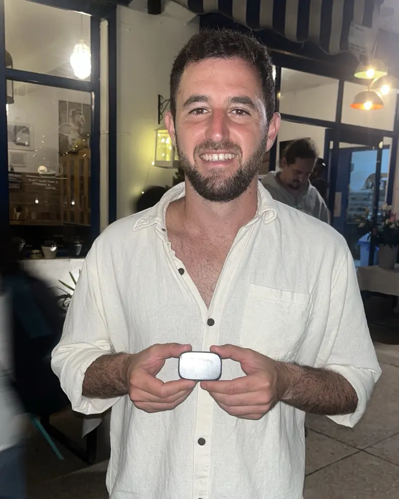 A bloc owner outside a blue and white cafe at night, holding a white bloc with both hands
