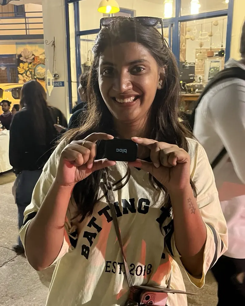 A bloc owner outside a warmly lit storefront at night, holding her bloc up with both hands