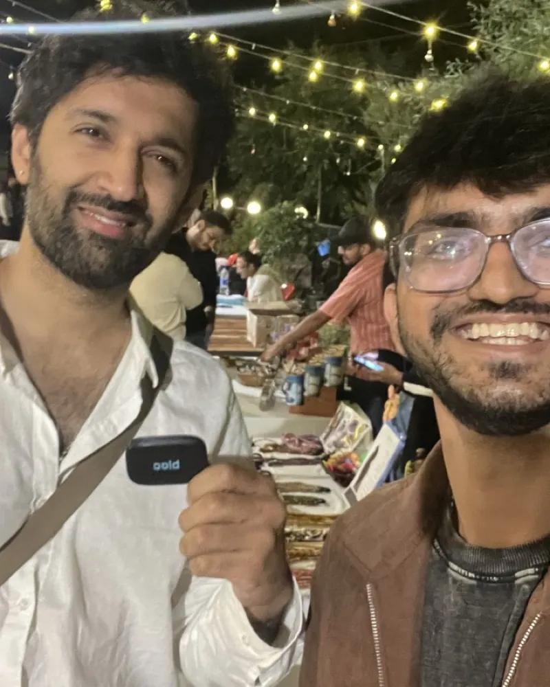 Two bloc owners at a night market lit by fairy lights, one holding his bloc at chest height